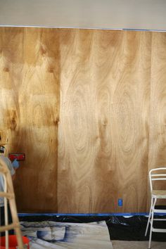 a room with wood paneling that is being worked on by someone using a paint roller