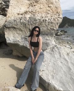 a woman sitting on top of a rock next to the ocean