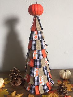 a decorated christmas tree sitting on top of a wooden table next to pine cones and pumpkins