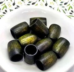 some black and green wooden tubes in a white bowl