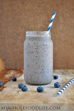 a blueberry smoothie in a mason jar with two striped straws