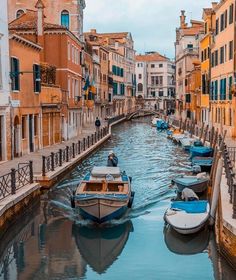 several boats traveling down a narrow canal between buildings