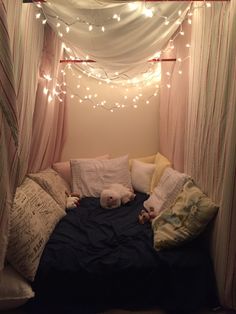 a bed with pillows and lights hanging from it's canopy over the headboard