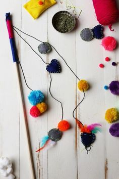 colorful pom - poms and other craft supplies laid out on a white wooden surface