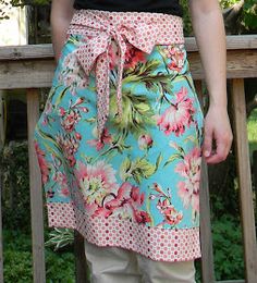 a woman standing on a porch wearing a blue floral apron with pink and green flowers