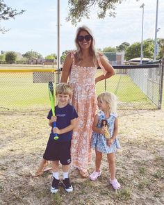 a woman standing next to two children holding tennis racquets in their hands