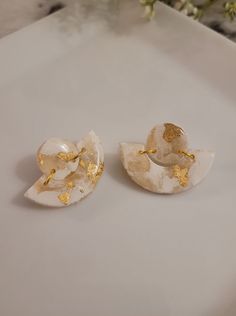 two white and gold earrings sitting on top of a table