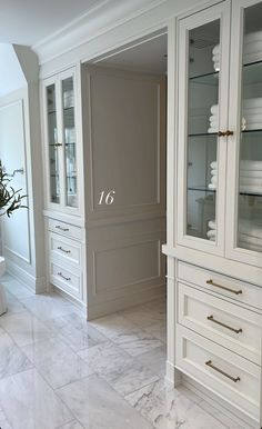 a bathroom with marble flooring and white cabinets in the corner, along with a vase filled with flowers