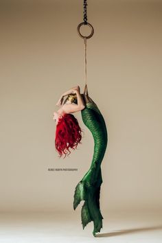 a mermaid hanging from a rope with her hands