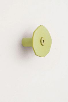 a yellow door knob on a white wall with a small hole in the middle that has a light green handle