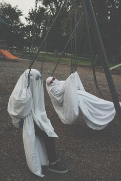 two people in white cloths on swings