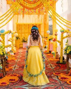 a woman in a yellow dress is walking down the aisle with flowers on her head