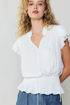 a woman with curly hair wearing a white top