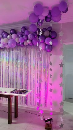 purple and silver balloons are hanging from the ceiling in front of a table with cupcakes on it