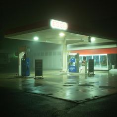 an empty gas station at night with the lights on and no one around it,