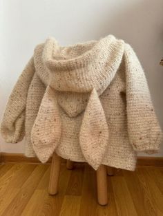 a white sweater sitting on top of a wooden stool