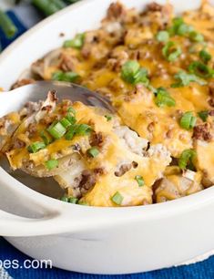 a casserole dish with meat, cheese and green onions in it on a blue cloth