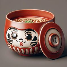 a red bowl with a cat design on it's side and the lid is made out of clay