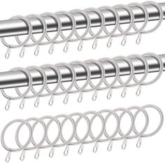 several metal hooks hanging from the side of a white wall with silver rings on them