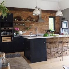 a kitchen with an island and bar stools next to it, in front of a brick wall