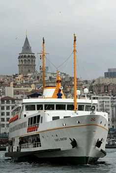 a large white boat floating on top of a body of water next to tall buildings