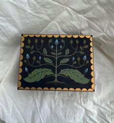 a black and yellow tray with a tree design on the bottom, sitting on a white sheet