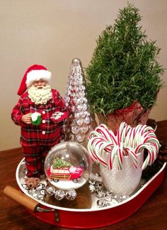 a santa clause doll sitting on top of a red wagon filled with candy canes