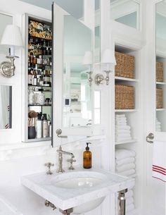 a bathroom sink sitting under a mirror next to a shelf filled with bottles and towels