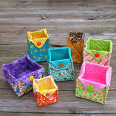 four different colored fabric baskets sitting on top of a wooden table next to each other