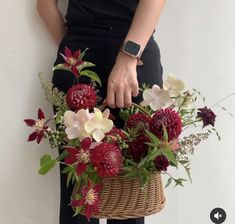 a person holding a basket with flowers in it