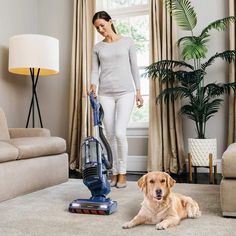 a woman is vacuuming the carpet with her dog