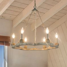 a chandelier hanging from the ceiling in a room with white walls and wood beams