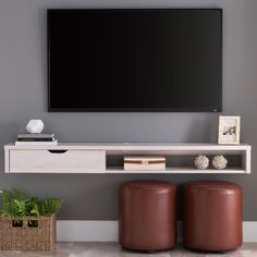 a flat screen tv mounted to the side of a wall above two brown stools