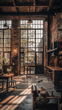 the sun shines through two large windows in an industrial style kitchen and living room