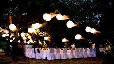 an outdoor dinner setup with white linens and lights