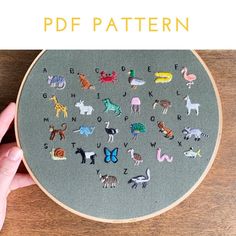 someone is holding up a cross - stitch project with animals and letters in the middle