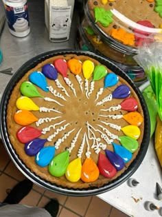 a cake decorated with colorful icing on top of a table next to other cakes