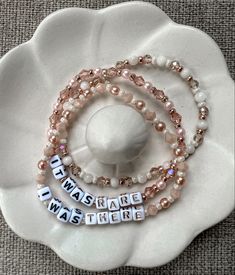 three bracelets with words on them sitting on top of a white flower shaped object