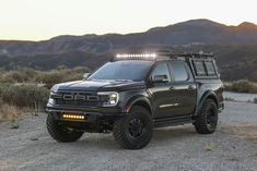 a black truck parked on top of a dirt field