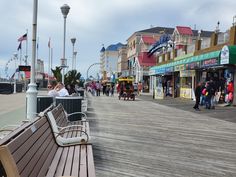 people are walking on the boardwalk near shops