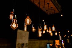 several light bulbs hanging from the ceiling in a dark room with lights all around them