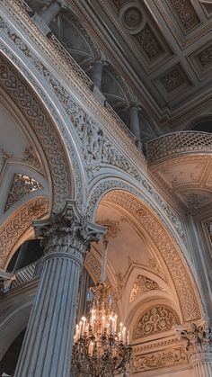 an ornate chandelier hangs from the ceiling in a building with columns and arches