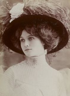 an old black and white photo of a woman wearing a hat with flowers on it