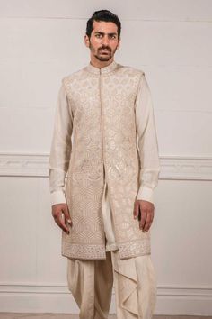 Ivory sleeveless sherwani with all-over applique, zardozi work paired with short kurta. Comes with dhoti pants.
Components:3
Embroidered
Neckline:Mandarin Collar
Sleeve Length:Kurta: Full; Sherwani: Sleeveless
Fabric:Katan silk, Raw silk
Color:White
Cuff sleeves
Side slits
Closure: Sherwani: Concealed front placket - Aza Fashions Elegant White Chanderi Nehru Jacket, Sleeveless Nehru Jacket With Resham Embroidery For Eid, Traditional Sleeveless Kurta For Reception, Festive Naqshi Bandhgala In Chanderi, Sleeveless Kurta For Eid Reception, Transitional Cream Chanderi Sherwani, Straight Kurta Nehru Jacket With Intricate Embroidery For Reception, Reception Nehru Jacket With Intricate Embroidery, Traditional Sleeveless Bandhgala With Chikankari Embroidery