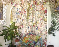 a living room filled with lots of furniture next to a window covered in colorful curtains