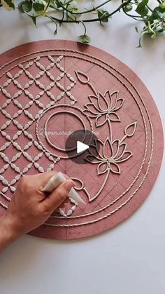 someone is making a flower design on a round surface with white flowers in the background