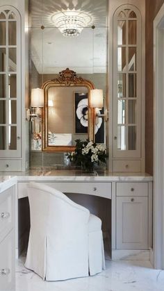 a white chair sitting in front of a vanity with a mirror on top of it