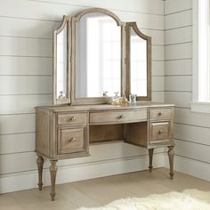 an antique style vanity with mirror and stool in a white painted room by a window