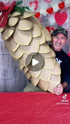 a man sitting in front of a giant paper mache that looks like a large piece of fruit