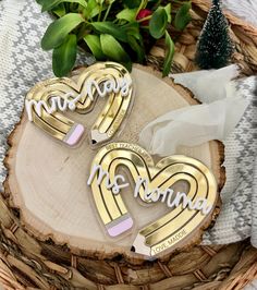 two heart shaped brooches sitting on top of a wooden slice next to a potted plant